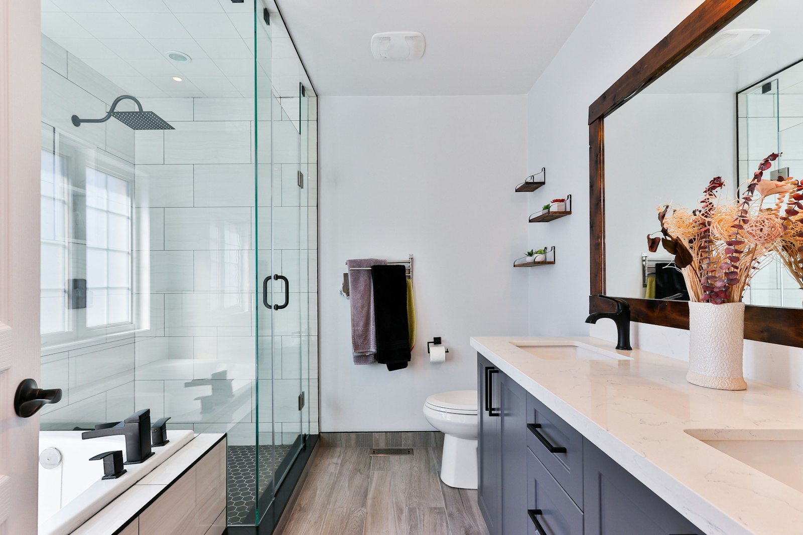 Modern saniertes Badezimmer mit ebenerdiger Glasdusche und schwarzen Armaturen