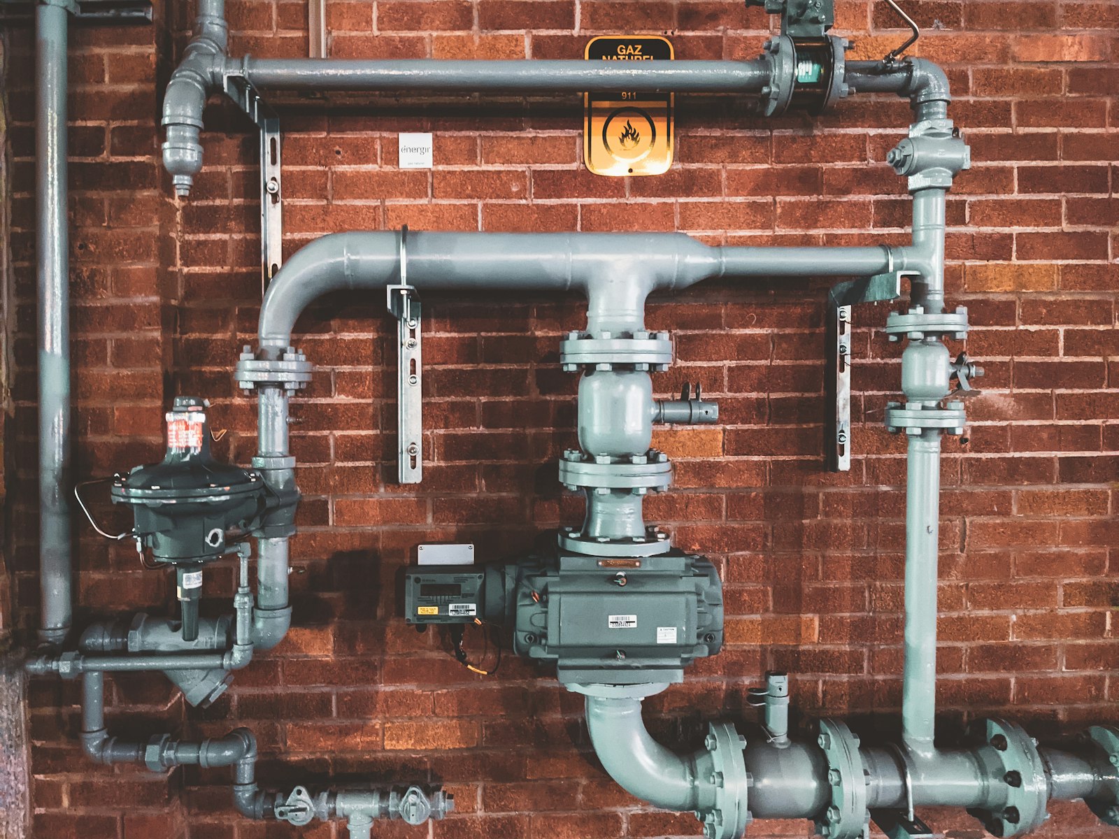 Fachgerecht installierte Gas- und Wasserleitungen an einer Ziegelwand